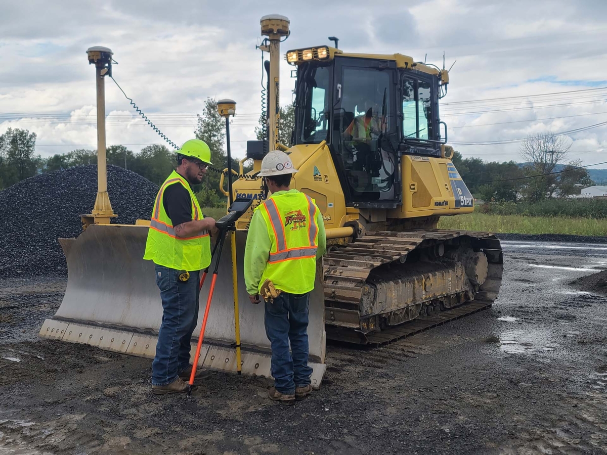 Two PKFI construction workers standing in front of a loader