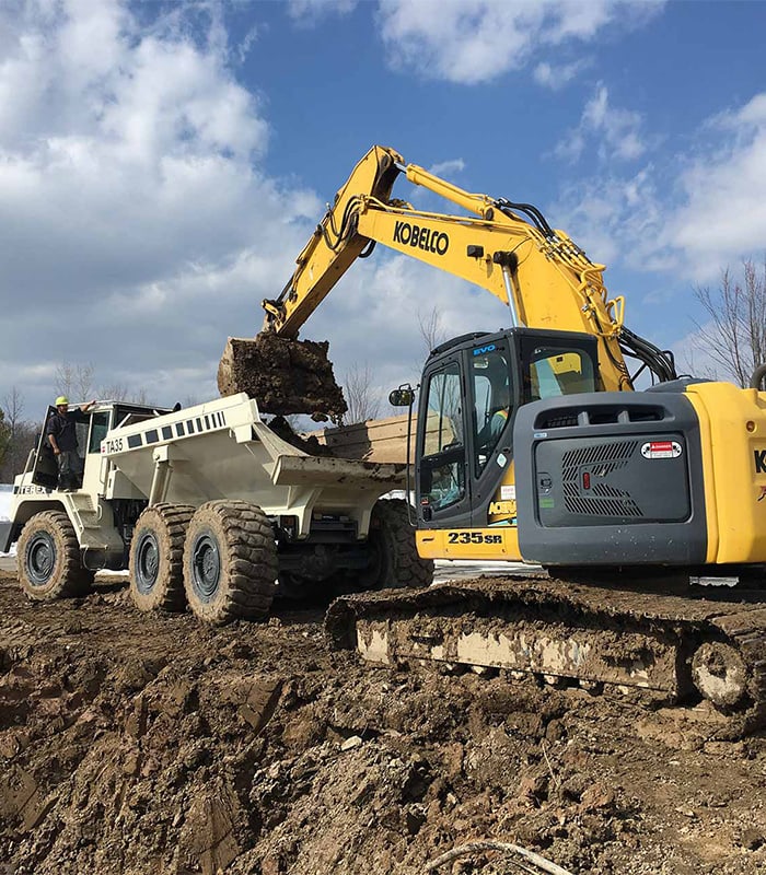 Excavator loading soil into dump truck