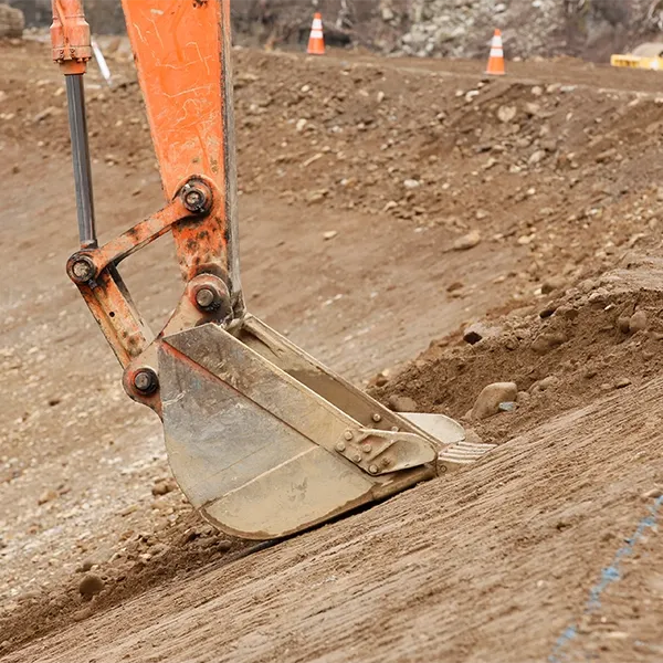 An excavator is digging into a dirt slope.