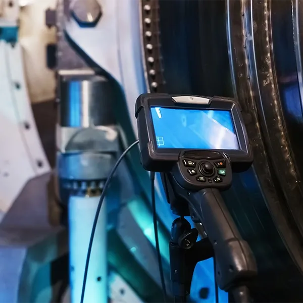 A camera with a screen is mounted to a tripod against an industrial backdrop.