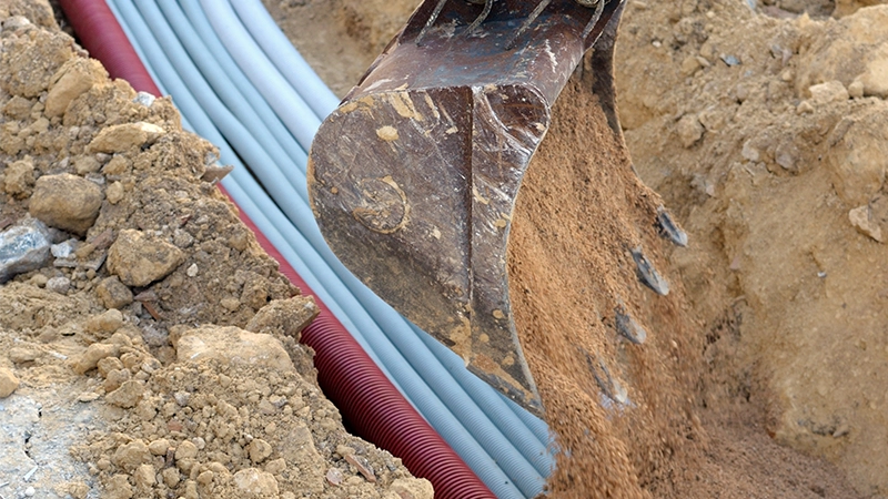 A construction site with a an excavator and electrical conduits.