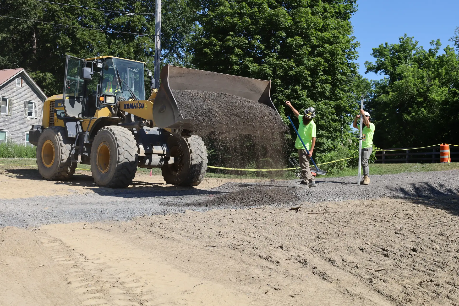 A construction worker is working near a bulldozer and another person stands nearby.