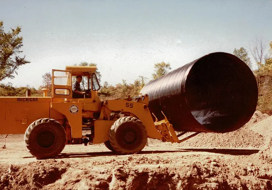 A historic photo of a large-scale pipe being transported.
